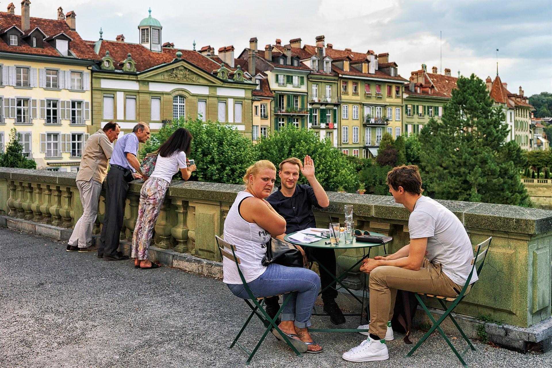 Bern’in eski şehrinde, Münsterplattform terasındaki açık hava kafesinde bir masada oturan arkadaşlar